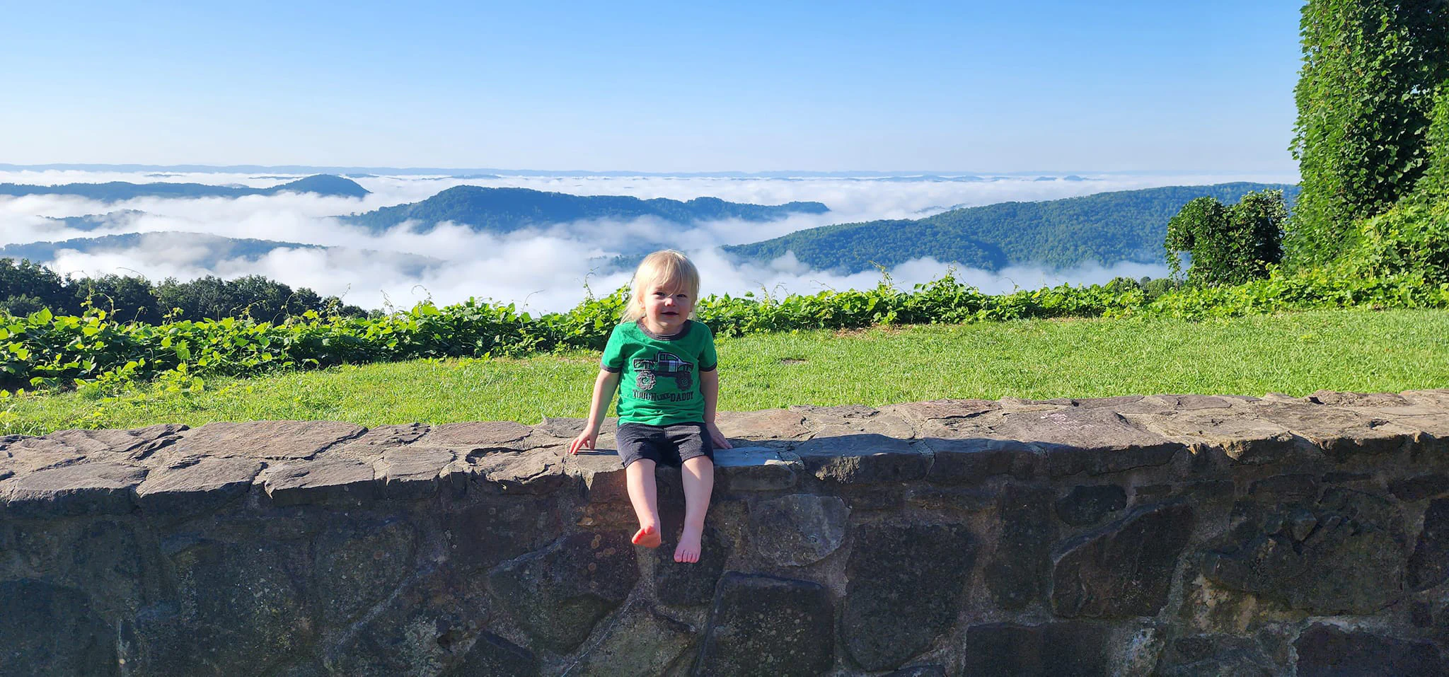 Sean sitting on a stone wall above a fog-filled valley